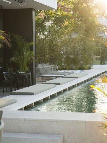 Moderner Poolbereich mit Sonnenliegen und Palmen im Abendlicht