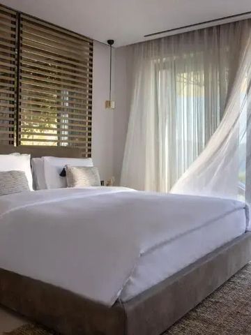 Helles Hotelzimmer mit Aussicht und eleganten Vorhängen.