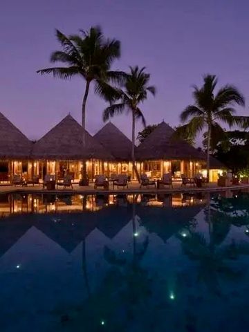 Beleuchtete Villa am Pool bei Sonnenuntergang auf Milaidhoo Island.