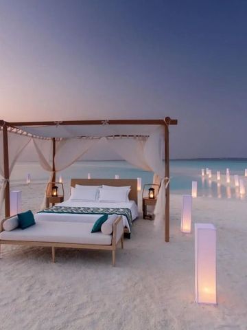 Romantisches Himmelbett am weißen Sandstrand in der Dämmerung auf Milaidhoo.