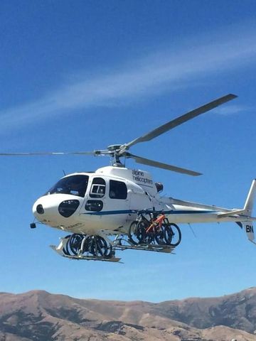 Helikopter mit Fahrrädern über Alpenlandschaft