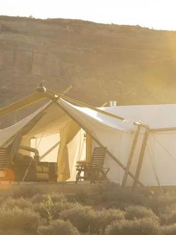 Zelt im Sonnenuntergang mit Stühlen und Tisch im Freien