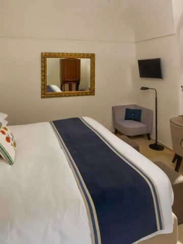 Elegantes Hotelzimmer mit Doppelbett, Spiegel und Schreibtisch im Monastero Santa Rosa