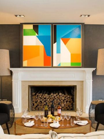 Gemütlicher Lounge-Bereich mit Kunstwerken über Kamin und Weinflaschen auf dem Tisch