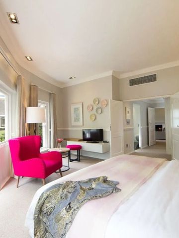 Helles Zimmer mit großer Fensterfront, rosa Akzenten und Gartenblick