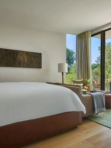 Hotelzimmer mit großem Fenster und Blick auf eine grüne Terrasse.