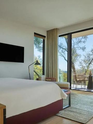 Helles Hotelzimmer mit großem Fenster und Terrasse mit Blick auf die Landschaft