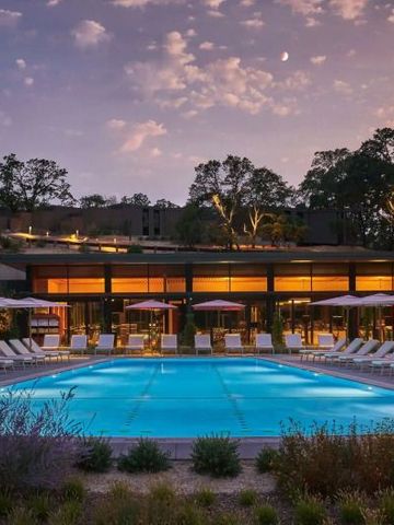 Beleuchteter Pool bei Dämmerung mit Sonnenliegen und moderner Architektur.