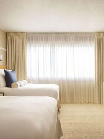 Modernes Hotelzimmer mit zwei Einzelbetten und stimmiger Beleuchtung.