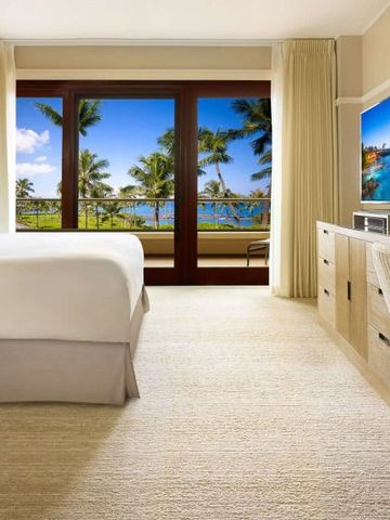 Helles Schlafzimmer mit Balkon und tropischem Meerblick.