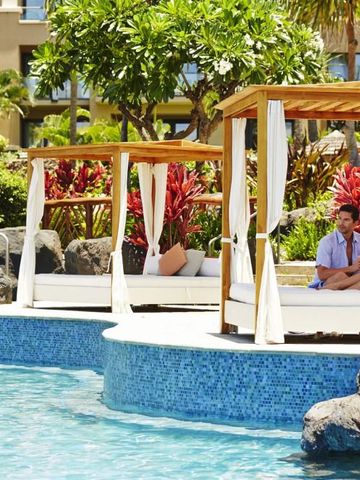 Sonnige Poollandschaft mit privaten Cabanas und üppiger Vegetation