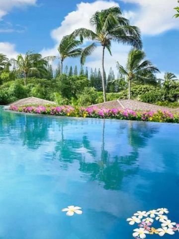Infinity-Pool mit Blumen und Palmen im Hintergrund unter blauem Himmel