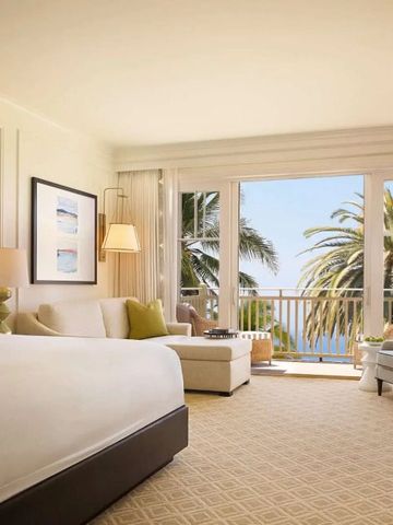 Komfortables Zimmer mit großen Fenstern, das auf einen Palmenblick und den Ozean öffnet.