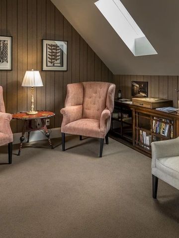 Gemütlicher Wohnbereich mit Sesseln und Bücherregal unter Dachschräge