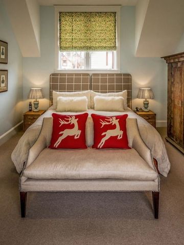 Elegantes Schlafzimmer mit rustikalem Schrank und roten Dekokissen