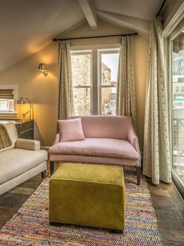 Heller Wohnraum mit zwei Sesseln, buntem Teppich und großen Fenstern