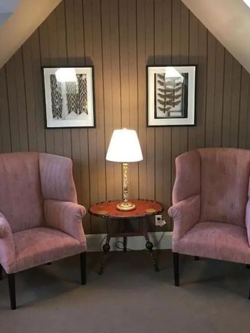 Gemütliche Sitzecke mit zwei Sesseln und einem kleinen Tisch unter schräge Decke