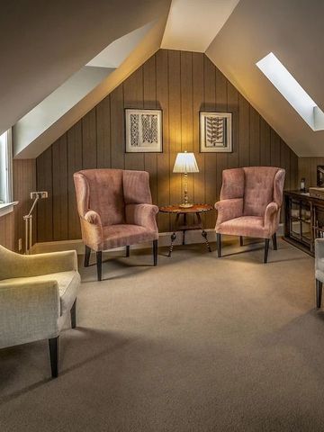 Stilvoller Wohnbereich unter Dachschräge mit mehreren Sesseln und Tisch