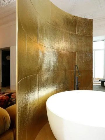 Elegantes Badezimmer mit goldener Akzentwand und freistehender Badewanne