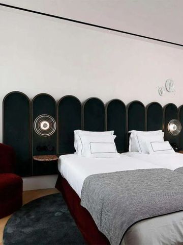 Doppelbett in modernem Hotelzimmer mit dunklem Kopfteil und roten Akzenten