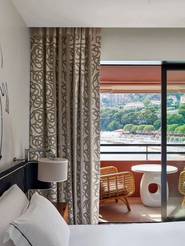 Zimmer mit stilvollem Balkonblick auf das Meer und moderne Kunst an der Wand.