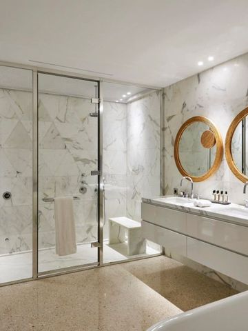 Geräumiges Badezimmer mit Marmordetails und zwei runden Spiegeln