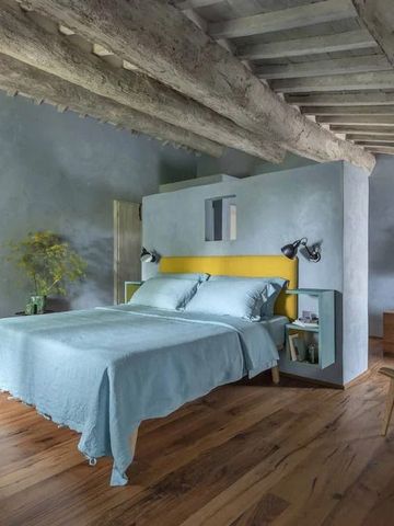 Stilvolles Zimmer mit Holzbalkendecke und Doppelbett in ruhigen Farben