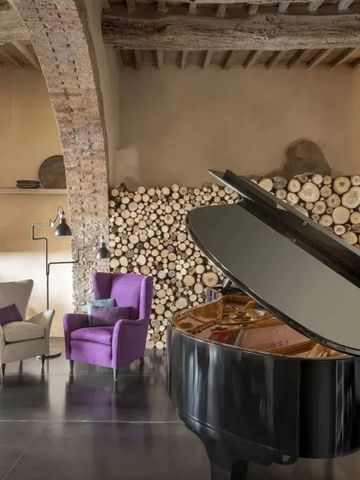 Elegante Lounge mit Flügel und lila Sessel neben gestapelten Holzscheiten