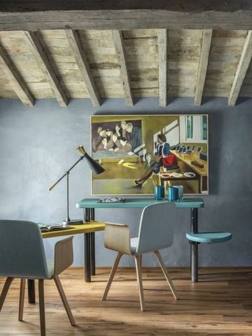 Kreativer Arbeitsbereich unter Balkendecke mit Kunstwerk und moderner Lampe