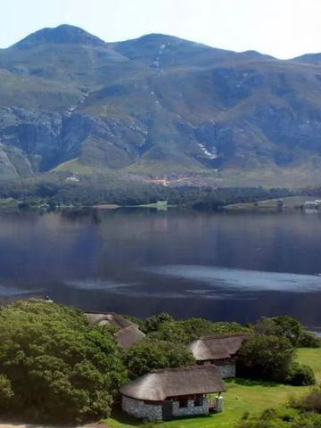 Weite Landschaft mit See und umliegenden Bergen sowie traditionellen Lodges