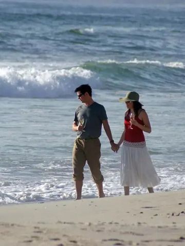 Pärchen spaziert am Strand entlang der ruhigen Meereswellen