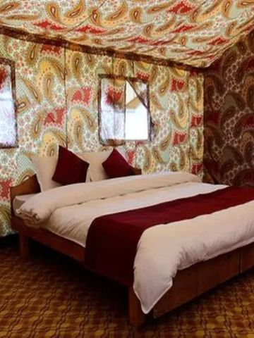 Luxuriös dekoriertes Zeltzimmer mit großem Doppelbett und buntem Stoffmuster