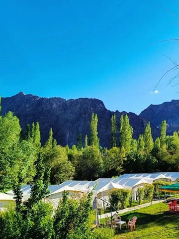Idyllische Landschaft mit Zelten und Bergen im Hintergrund