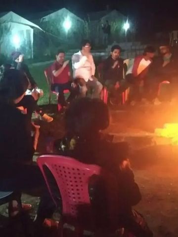 Gruppe von Personen sitzt um ein Lagerfeuer bei Nacht im Freien