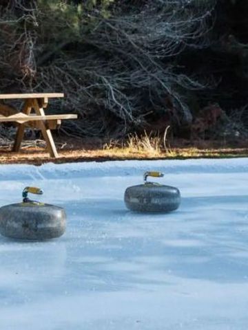 Eisbahn mit Curling-Steinen in einer bewaldeten Umgebung