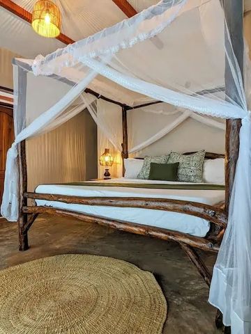 Großes Himmelbett mit weißen Vorhängen in rustikalem Ambiente