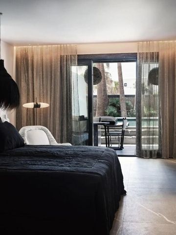 Elegantes Zimmer mit großem Bett und Blick auf Balkon mit Palmen