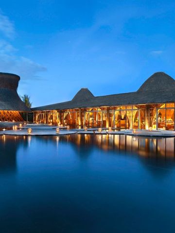 Beleuchtete Hotelarchitektur bei Nacht mit Reflektionen im Wasser