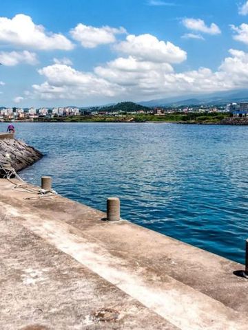Klarer blauer Hafen mit Leuchtturm und Stadt im Hintergrund