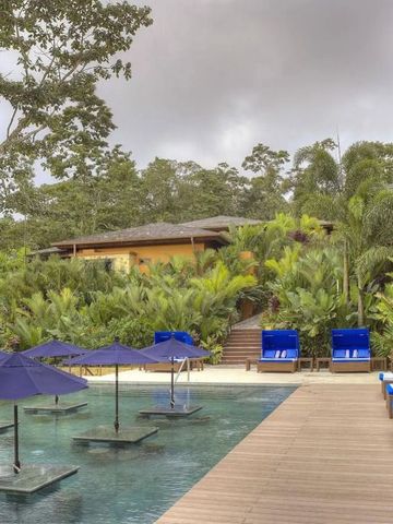 Elegant gestalteter Pool mit blauen Sonnenschirmen umgeben von tropischem Grün