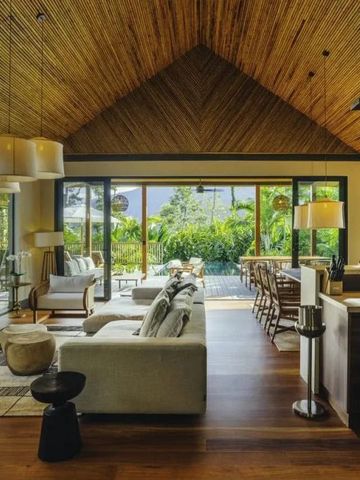 Luxuriöser Wohnbereich mit offenem Holzdach und Blick auf den tropischen Garten