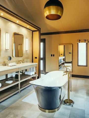 Elegantes Badezimmer mit freistehender Badewanne und goldenen Armaturen