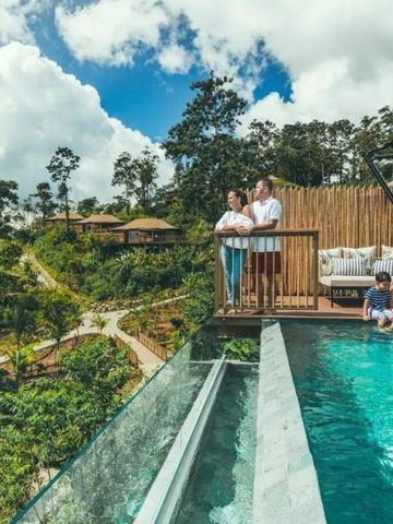 Familie am Rand eines Infinity-Pools mit Blick auf die üppige tropische Landschaft
