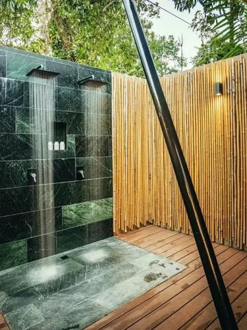 Freiluft-Dusche mit Bambuswänden und schwarzem Marmor in tropischer Umgebung