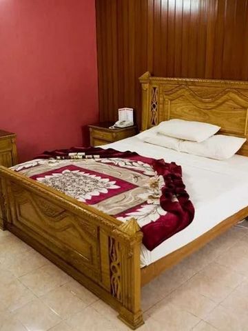 Holzbett mit dekorativer Decke in gemütlichem Zimmer mit roten Wänden