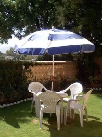 Gartenmöbel mit Sonnenschirm im grünen Außenbereich