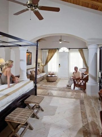 Elegantes Zimmer mit Himmelbett und Sitzbereich in neutralen Tönen