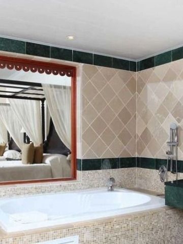 Badezimmer mit eingelassener Badewanne und grünem Marmordekor