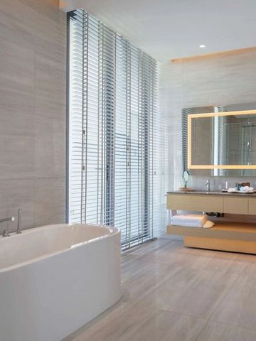 Geräumiges Badezimmer mit freistehender Badewanne und großen Fenstern