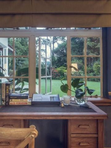 Schreibtisch an einem Fenster mit Blick auf einen grünen Garten